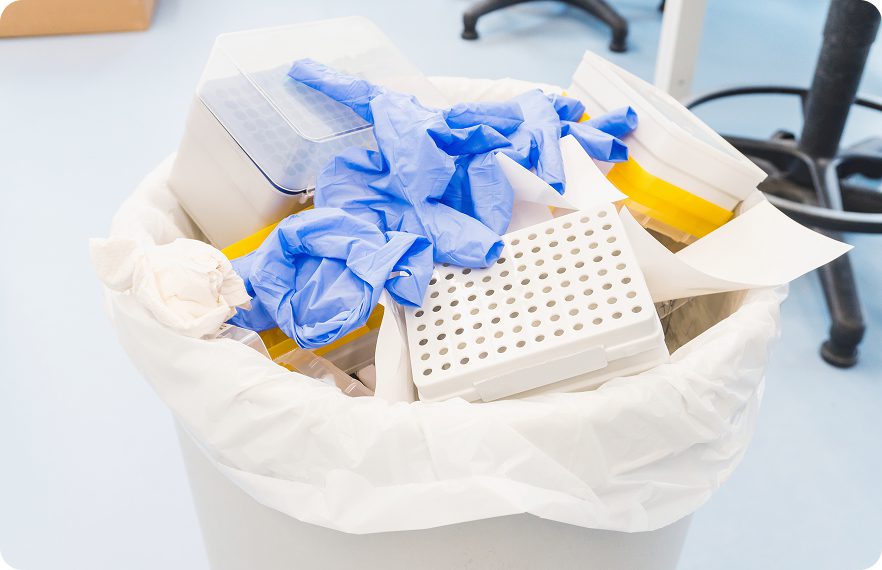 Trash bin with laboratory waste and gloves.