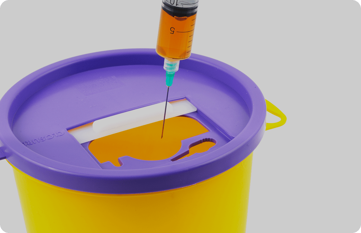 Syringe discarding into yellow medical container.