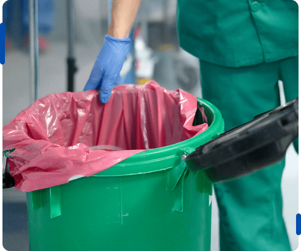 Medical professional handling a red biohazard waste bin liner.